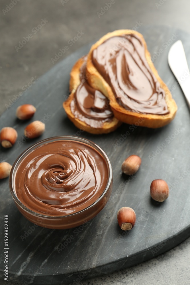 Tasty chocolate spread, toasts and hazelnuts on gray table, closeup Tasty chocolate spread, toasts and hazelnuts on gray table, closeup