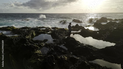 Wallpaper Mural Drone hovers over tide pools facing the sunset with a silhouette standing on the rocks as waves crash the shores Torontodigital.ca
