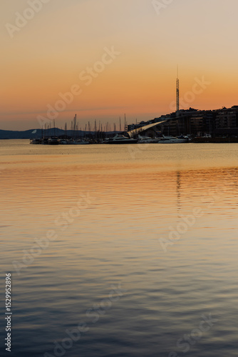 Canvas Print Bathed in the warm glow of sunset, Oslo harbour showcases traditional colourful wooden houses along the waterfront, with boats gently berthed in the distance