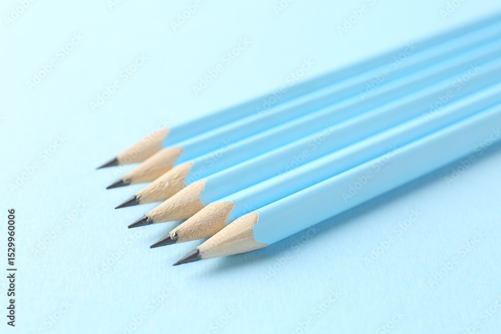 Fototapeta premium Graphite pencils on light blue background, closeup