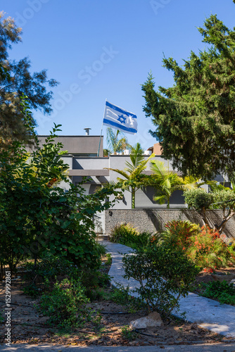 Canvas Print Modern residential house with Israeli flag and lush green garden on a sunny day in Ashkelon, Israel