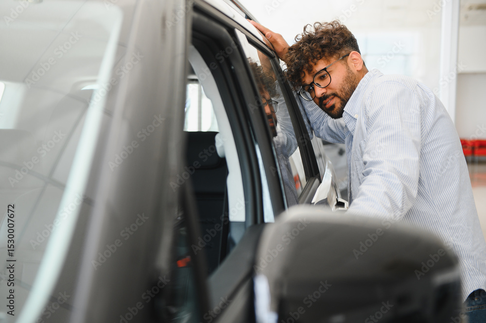 Customer examining new car in dealership showroom. Customer examining new car in dealership showroom.