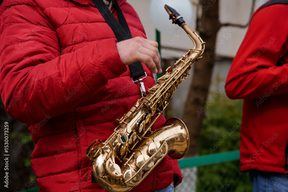 Obraz premium Saxophone Player in Red Puffer Jacket Outdoors, Street Performance, Brass Instrument, Urban Music Scene, Dynamic Shot, Golden Tone.