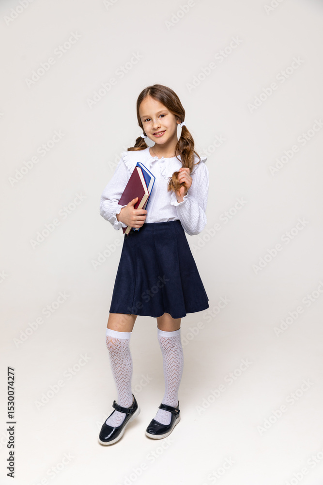 Fototapeta premium Portrait of happy girl with school books on white background. Little happy school girl going to school, back to school, education concept. Cute female student smiling and looking at camera