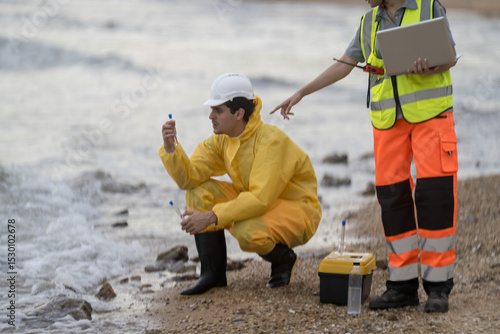 Slika na platnu Environmental scientists collect water samples at the beach during a sunny day f