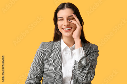 Beautiful happy young businesswoman laughing on yellow background