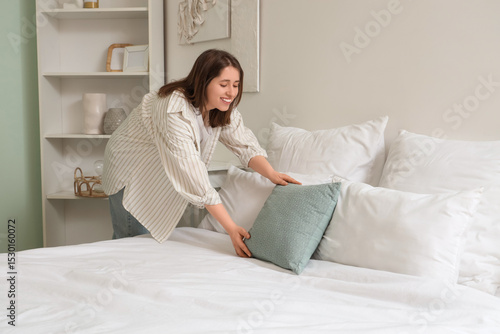 Young woman putting pillows...