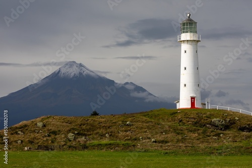 Cape Egmont Lighthouse stands tall on the coast of Pungarehu, Taranaki, New Zealand, guiding ships safely. The iconic landmark is set against the backdrop of Mount Taranaki.