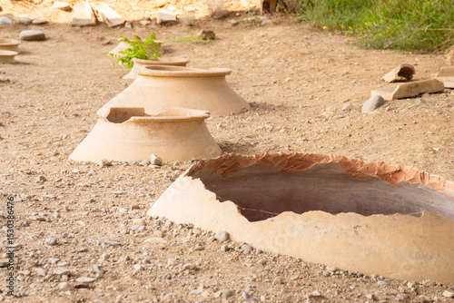 Clay wine vessels embedded in earth beneath wooden shelter at Armaziskhevi site, part of an ancient wine making cellar in Mtskheta region, Georgia