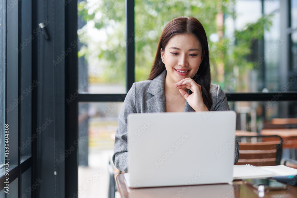 Young Asian businesswoman using laptop in cafe, smiling and looking at screen, working remotely or studying online Young Asian businesswoman using laptop in cafe, smiling and looking at screen, working remotely or studying online