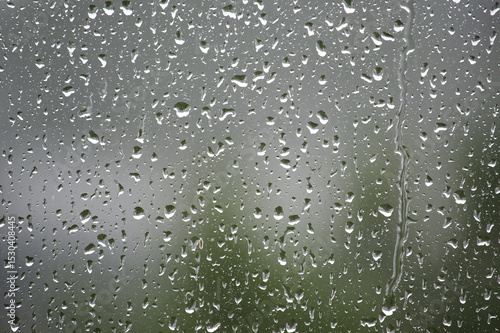 Raindrops on a window create a beautiful, abstract scene with a blurred background.