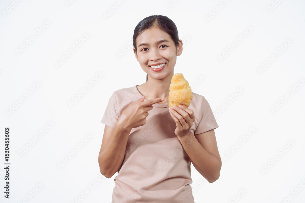 A confident young Asian woman in a light brown shirt stands against a white background, happily holding a delicious croissant in her hand, ready to enjoy a fresh and tasty pastry snack. A confident young Asian woman in a light brown shirt stands against a white background, happily holding a delicious croissant in her hand, ready to enjoy a fresh and tasty pastry snack.