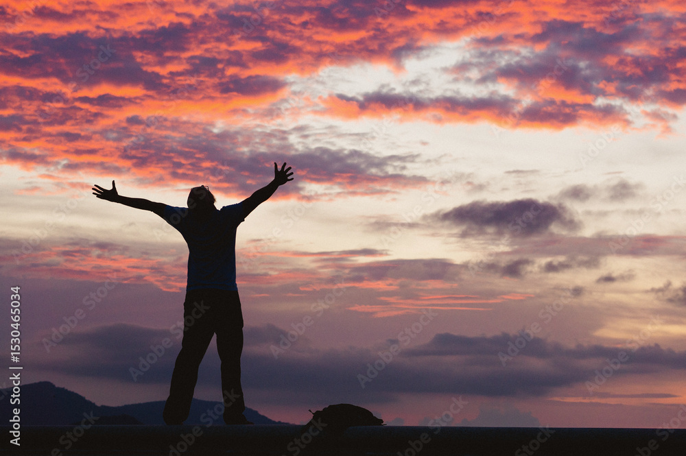 Fototapeta premium Silhouette of a person celebrating at sunset