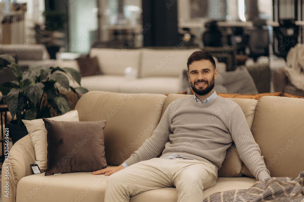 Young Man Relaxing on Stylish Sofa in a Modern Furniture Store Young Man Relaxing on Stylish Sofa in a Modern Furniture Store
