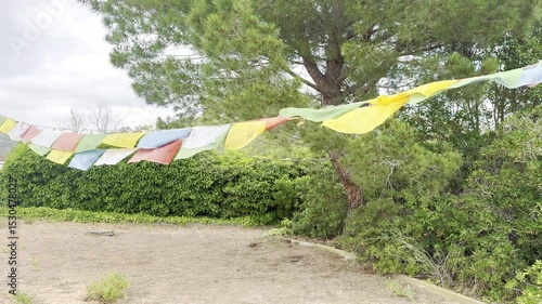 prayer flags flutter in the wind at a buddhist monastery in garraf spain