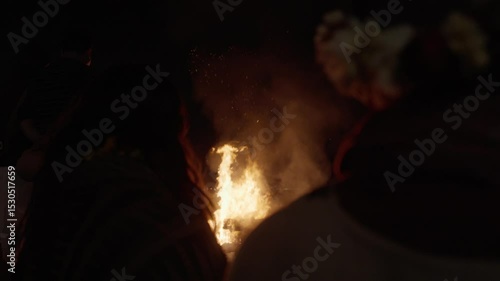 Varanasi, Uttar Pradesh, India-24th February 2025- Over the shoulder high speeds shot of a man watching human body getting burned on wooden deck after the death.