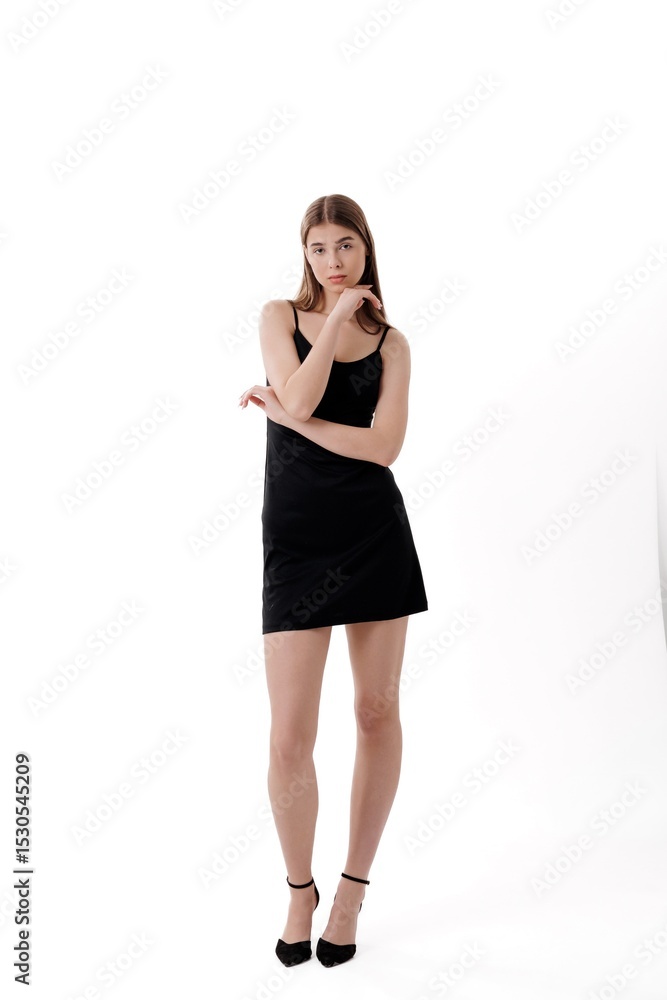 Fototapeta premium Model poses confidently in a black dress with elegant heels in a minimalist studio setting