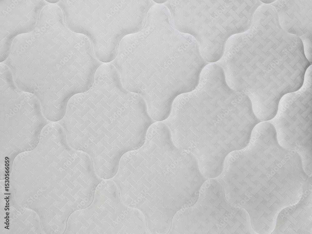 Naklejka premium A close-up view of a white quilted mattress surface with geometric stitching and padded texture, showcasing textile detail and comfort design.