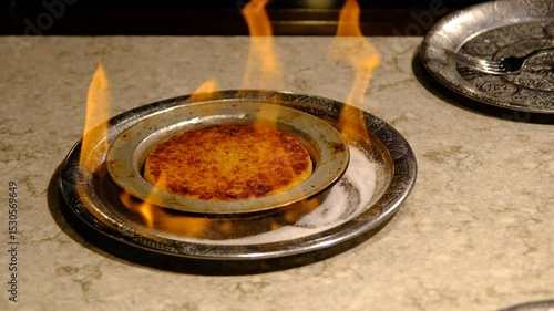 Close-up view of Kunefe being prepared on a stovetop with melted cheese and golden crispy pastry.
