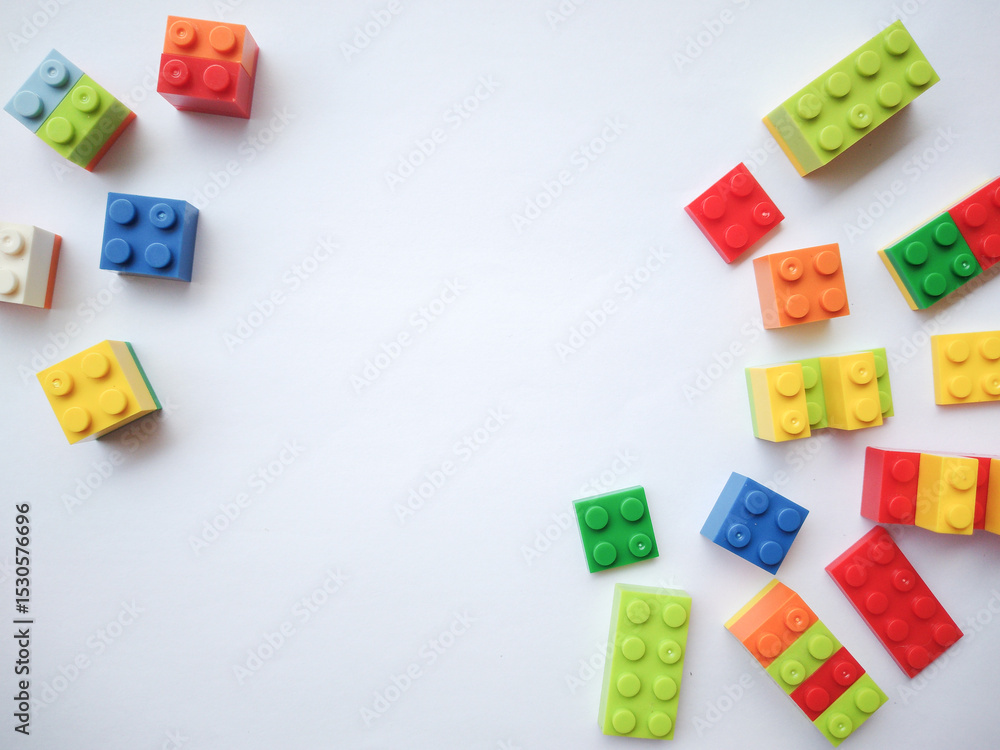 Obraz premium Colorful plastic bricks on white background. Educational toys for kids mockup, top view. Concept of education, children's creativity. Copy space.