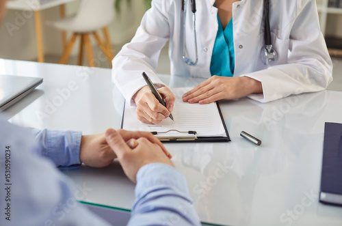 Female doctor, general practitioner filling paper medical records consulting patient in clinic, GP talking to discuss, checkup results with client at meeting hospital, share treatment plan, therapist
