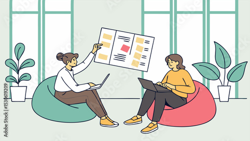 Two women working on laptops while discussing a project board in a bright and modern office space