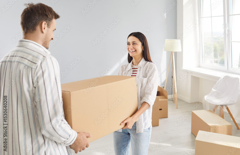 Young happy smiling couple carrying unpacking cardboard boxes in new apartment celebrating moving day. Cheerful family buy a property. Move, relocating, real estate, mortgage concept. Young happy smiling couple carrying unpacking cardboard boxes in new apartment celebrating moving day. Cheerful family buy a property. Move, relocating, real estate, mortgage concept.