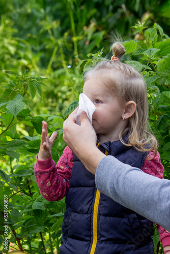 Fotografie Father helps little girl wipe snot from her nose due to spring allergies