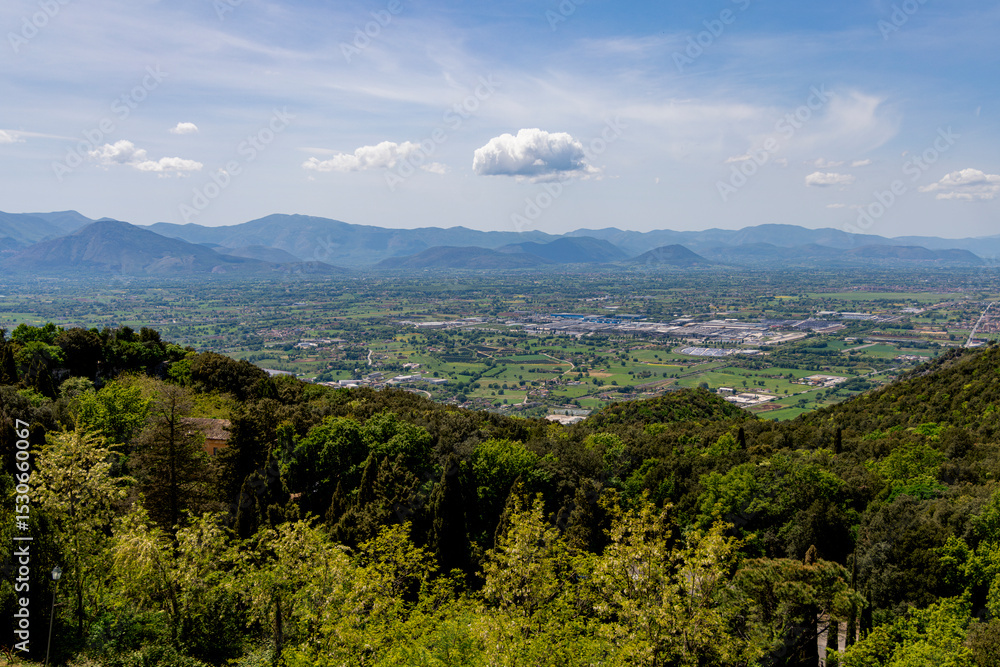 Fototapeta premium A breathtaking aerial view of Cassino, Italy, surrounded by verdant hills and distant mountains under a clear blue sky