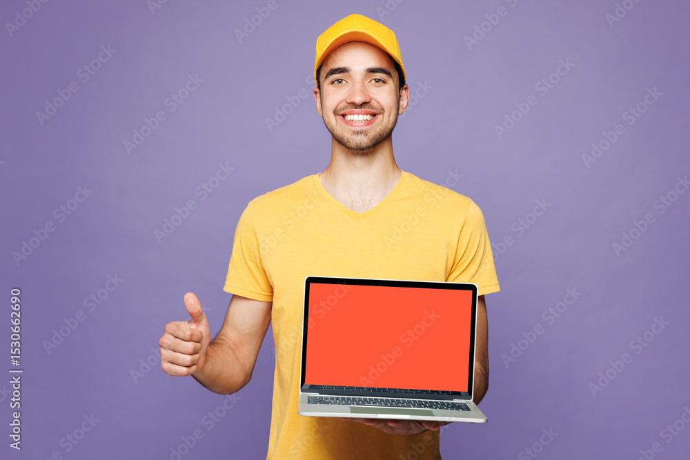 Young delivery guy IT man wear yellow cap t-shirt uniform workwear work as dealer courier hold use blank screen laptop pc computer show thumb up isolated on plain purple background. Service concept. Young delivery guy IT man wear yellow cap t-shirt uniform workwear work as dealer courier hold use blank screen laptop pc computer show thumb up isolated on plain purple background. Service concept.