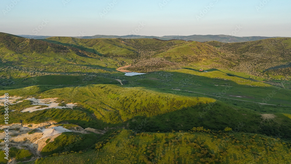 Fototapeta premium Buzău Green Hills Sunset. A serene landscape view captures rolling green hills in Buzău County, Romania, bathed in the warm hues of a sunset. 