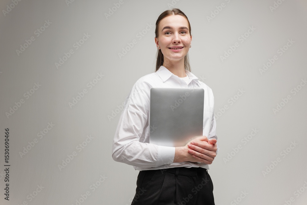Young Woman Confidently Holds a Laptop While Smiling in a Professional Setting During Daylight Young Woman Confidently Holds a Laptop While Smiling in a Professional Setting During Daylight