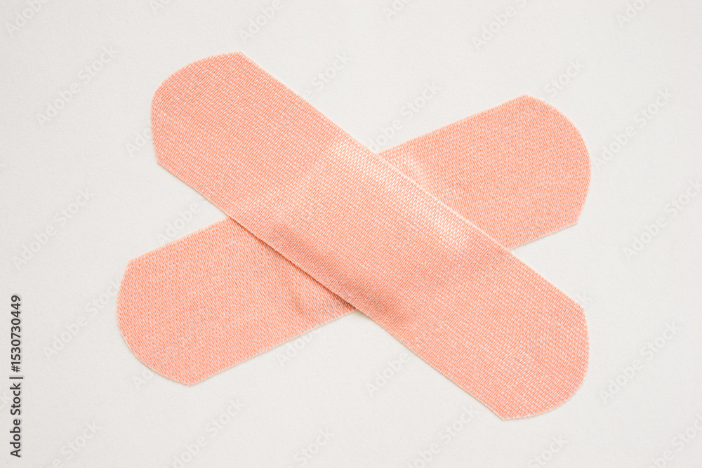 Two adhesive bandages crossed on white background Two adhesive bandages crossed on white background