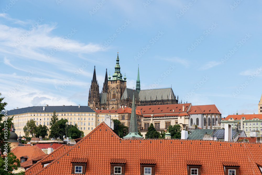 A picturesque view of Prague Castle and surrounding historical architecture, with reflections on the Vltava River under a cloudy sky A picturesque view of Prague Castle and surrounding historical architecture, with reflections on the Vltava River under a cloudy sky