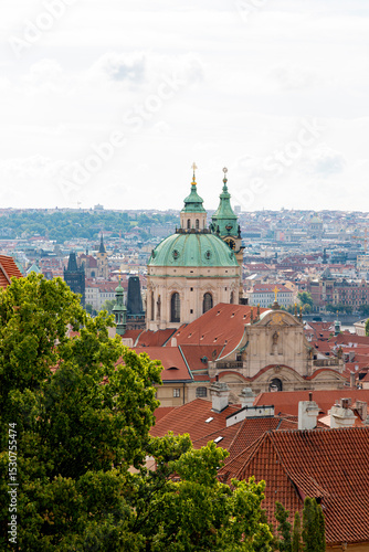Wallpaper Mural A wide-angle view of Prague’s iconic red rooftops, historic churches, and lush green surroundings. The cityscape combines traditional architecture with glimpses of modern structures in the background Torontodigital.ca