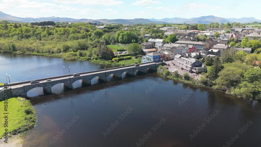 Aerial view of Killorglin, County Kerry. Calm river, stone bridge, rower gliding by charming Irish town houses. Serene and scenic Irish countryside. Aerial view of Killorglin, County Kerry. Calm river, stone bridge, rower gliding by charming Irish town houses. Serene and scenic Irish countryside.