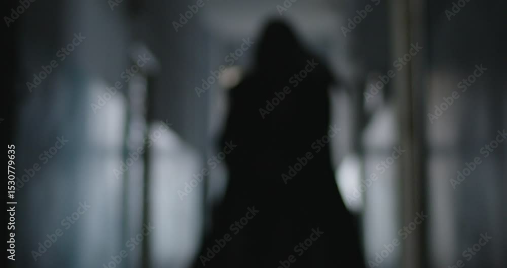 Sinister black silhouette of grim reaper death quickly approaching camera, swinging his scythe. Mysterious figure dressed in hooded black cloak running at you, creating sense of fear and anxiety.