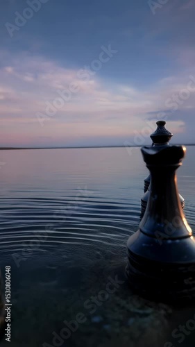Strategic chess pieces rise from serene waters at sunset, symbolising game, strategy, planning, and reflection by the lakeside.