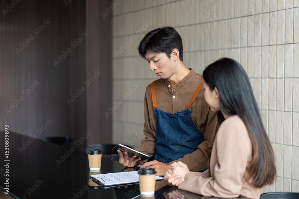 Fototapeta premium Entrepreneurial Collaboration. Young professionals reviewing plans with a tablet in a cafe.