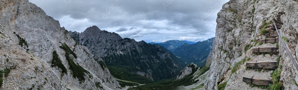 Fototapeta premium Panoramic view of Logarska dolina valley with peaks of Slovenian Alps covered by passing clouds.