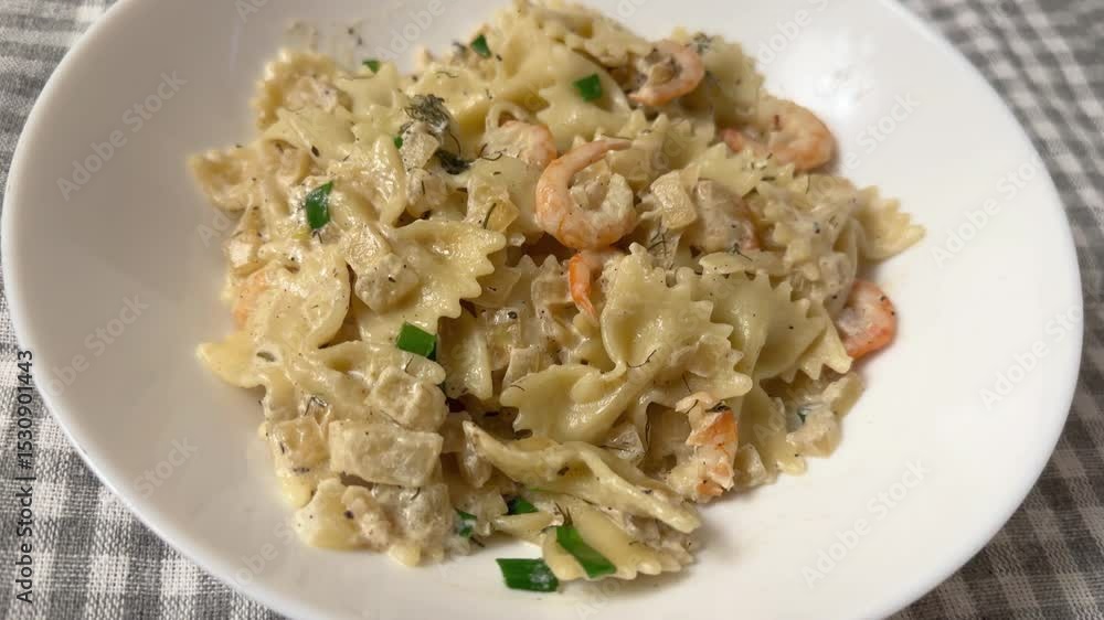 Cooked butterfly shaped pasta with boiled shrimp tails on dish Cooked butterfly shaped pasta with boiled shrimp tails on dish
