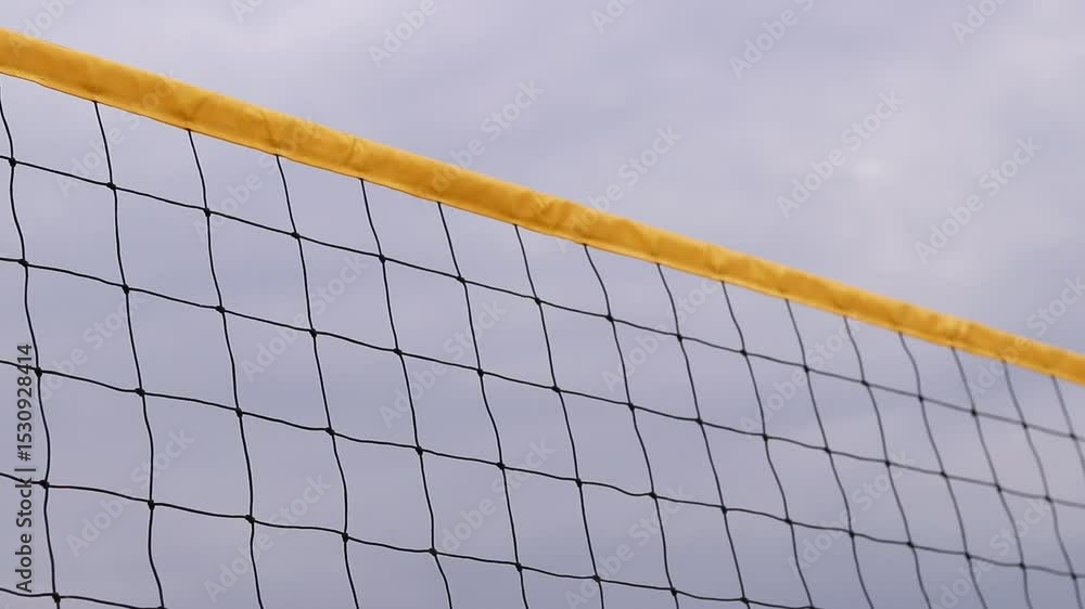 Beach volleyball net close-up. Volleyball net fragment on the beach against the sky. Sport, beach volleyball. Active recreation concept. Background. Yellow net detail. Sports ground Beach volleyball net close-up. Volleyball net fragment on the beach against the sky. Sport, beach volleyball. Active recreation concept. Background. Yellow net detail. Sports ground