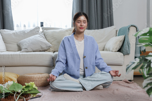 Foto Young woman meditating peacefully at home, sitting cross legged on carpet, pract