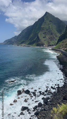 Scenic coastal view of São Vicente, Madeira, Portugal, with waves crashing against a rocky shoreline beneath towering green cliffs.