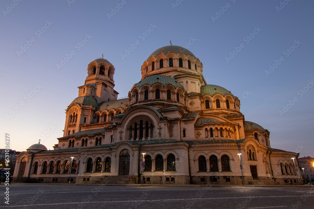 Fototapeta premium The majestic Alexander Nevsky Cathedral in Sofia, Bulgaria, illuminated by soft evening light, showcasing its impressive architecture and iconic domes in a serene twilight setting.