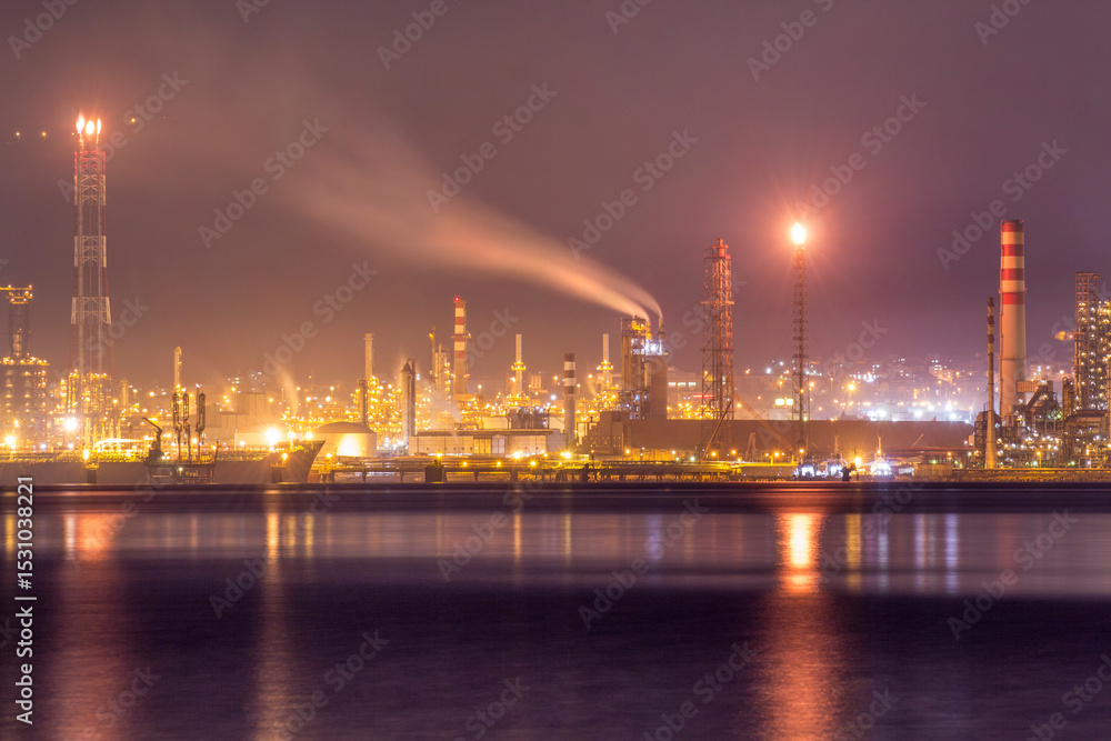 Fototapeta premium Night view of Tüpraş oil refinery in İzmit, Turkey. Industrial lights reflect on water, showcasing the complex refinery infrastructure, highlighting energy production and petroleum processing.