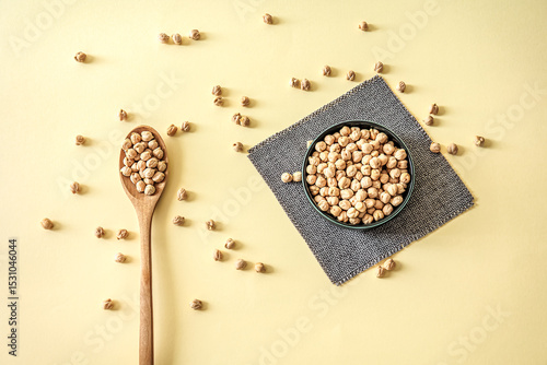 Wallpaper Mural Dried chickpeas in a bowl and wooden spoon on yellow pastel background. Healthy plant-based protein, minimal composition with natural light and soft color mood Torontodigital.ca