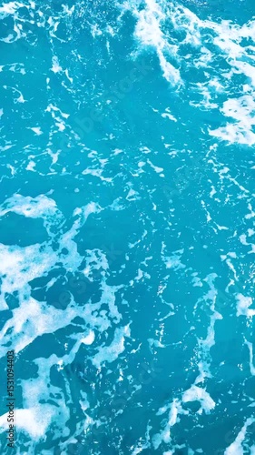 Rich bright blue turbulent water of warm turquoise sea with foam, sunny summer day from travel and relaxing vacation, Serene ocean texture slow motion vertical background, Fresh landscape from yacht