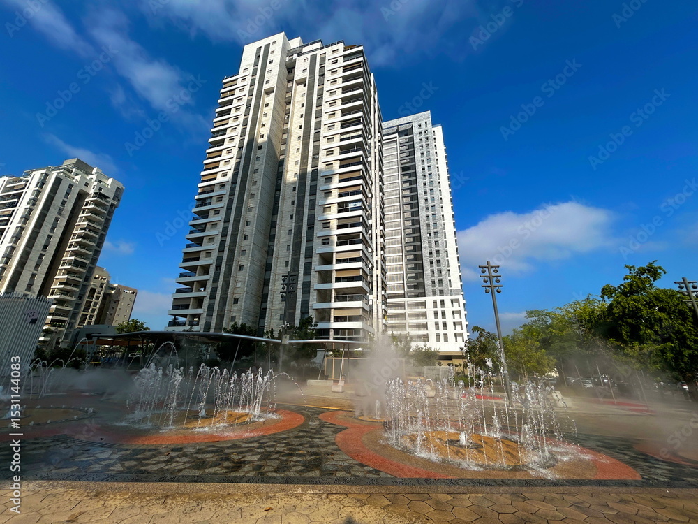 Fototapeta premium Fountain in the middle of a modern residential area. Multi-storey apartment buildings, Israeli city. Comfortable housing