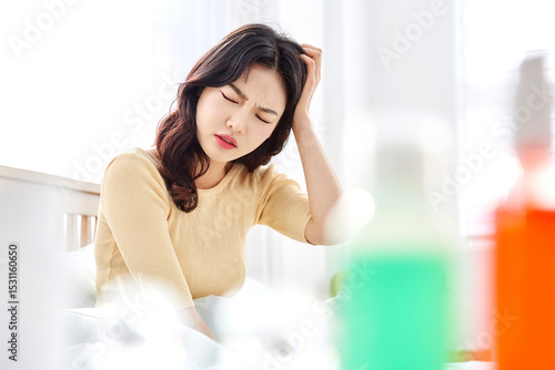 Young Asian Woman in Yellow Sweater Sitting on Bed, Holding Head in Pain, Suffering from Headache in Bright Morning Light Free Download Young Asian Woman in Yellow Sweater Sitting on Bed, Holding Head in Pain, Suffering from Headache in Bright Morning Light - GFXLoad